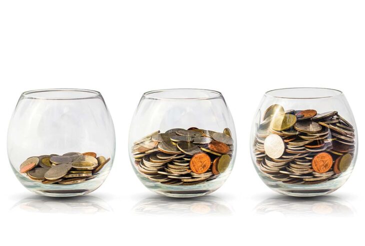 Three glasses with coins inside against white background